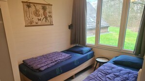 Quarto pequeno com duas camas, uma janela e um quadro na parede.