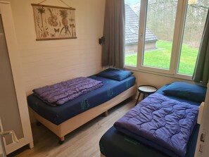 Ein kleines Zimmer mit zwei Betten, einem Fenster und einem Wandbild.