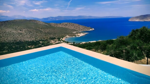 Ein Schwimmbecken mit Blick auf das Meer und die Berge.