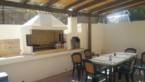 Eine Terrasse im Freien mit Grill, Stühlen und Tisch.