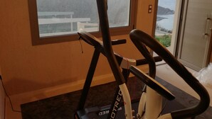 Ein stehendes Fahrrad in einem Raum mit einem großen Fenster mit Blick auf eine Berglandschaft.