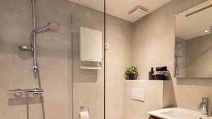 Ein modernes Badezimmer mit einer Glasdusche, einer weißen Toilette und einem Holzausleger mit Waschbecken.