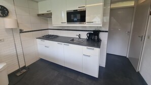 Una cocina moderna con armarios blancos, una estufa a gas, una cafetera y un microondas.