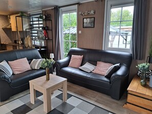 A modern living room with two black leather sofas, a wooden coffee table, and a black and white patterned rug. - RBR 1233 - Beach Resort Kamperland by Interhome (Kamperland)