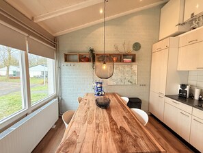 Eine moderne Küche mit Holztisch, weißen Schränken und einer Pendelleuchte.