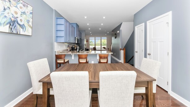 Una cocina moderna con armarios azules, una mesa de comedor con sillas y un ventanal grande.