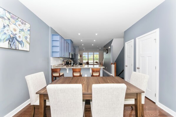 A modern kitchen with blue cabinets, a dining table with chairs, and a large window.