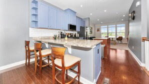 Una cocina moderna con armarios azules, una isla de granito y taburetes de madera.