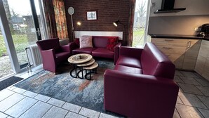 Ein modernes Wohnzimmer mit einer Sofagarnitur, einem Couchtisch und Blick ins Freie.