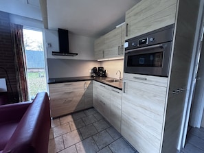 A modern kitchen with a built-in oven, a coffee maker, and a sink. - Bungalowpark Simpelveld - Delta 112 by Interhome (Simpelveld)