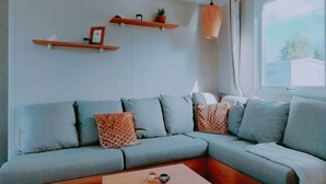 Een moderne woonkamer met een hoekbank, een houten salontafel en wandplanken.