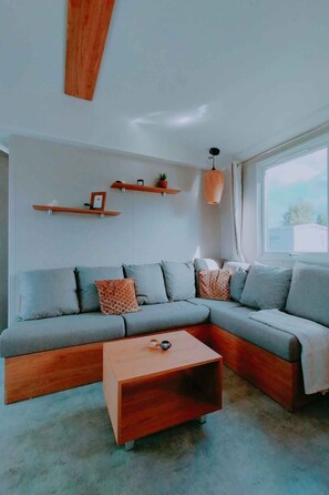Ein modernes Wohnzimmer mit einem Ecksofa, einem Holztisch und Wandregalen.