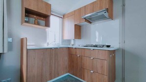 Een kleine keuken met houten kastjes, een gasfornuis en een inbouwoven.