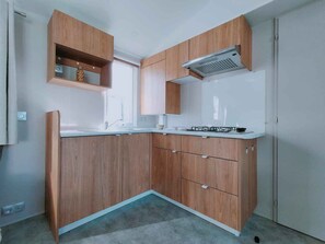 Eine kleine Küche mit Holzausstattung, einem Gasherd und einem Backofen.