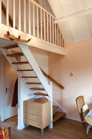 Eine Treppe mit Holzbalken und weißen Geländern, die zu einer oberen Etage führt.