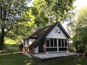 Ein eingeschossiges Haus mit Satteldach, einer Garage mit großen Fenstern und einem kleinen angebauten Geräteschuppen.
