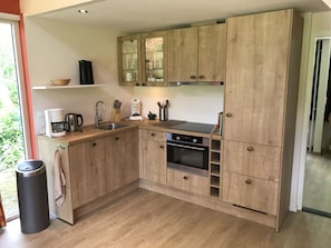Eine moderne Küche mit Holzschränken, einem eingebauten Backofen und einer Kaffeemaschine.