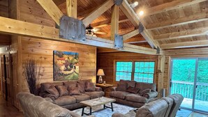 A log cabin interior with a sectional sofa, a coffee table, and a painting on the wall.