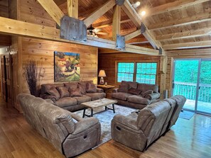 A log cabin interior with a sectional sofa, a coffee table, and a painting on the wall. - Cozy Waterfront Log Cabin Retreat on a Quiet Creek (Mineral)