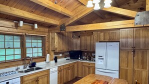 A wooden kitchen with a central island, a built-in dishwasher, and a refrigerator.