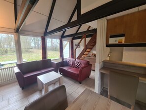 Ein Wohnzimmer mit einer Couch, einem Tisch und einer Küchenzeile mit Arbeitsfläche und Schränken.