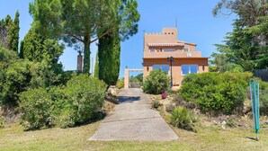 A pathway leading to a building with a tiled roof and a flat roof section. - Villa “My Little Castle Platja D'Aro” with Sea View, Balcony and Wi-Fi (Castell d'Aro)