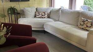 A living room with a beige sectional sofa, a red armchair, and a small side table with a plant. - Bungalowpark Simpelveld - Alpha 89 by Interhome (Simpelveld)