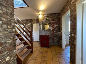 Ein Zimmer mit einer Holztreppe, einer weißen Tür, einem roten Schrank und einem Fliesenboden.