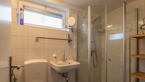 Une salle de bain équipée de toilettes, d’un lavabo, d’une douche et d’une fenêtre.