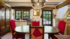 A rustic dining area with wooden furniture, a chandelier, and stone walls.