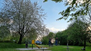 Ein Park mit Spielgeräten, Bänken und Bäumen.