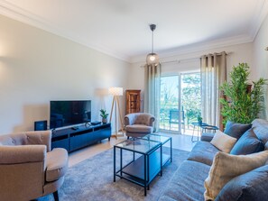 A modern living room with a flat-screen TV, a glass coffee table, a sofa, and a chair. - Fairviews Village - Boavista Resort in Lagos by Interhome (Lagos)