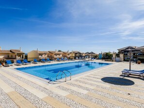 Une piscine avec des chaises longues et une terrasse carrelée.