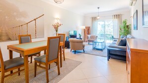 Ein modernes Wohnzimmer mit Essbereich, einer Couch, einem Fernseher und einer Treppe.