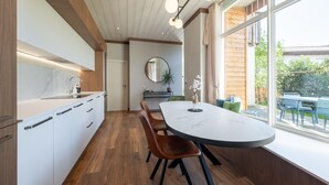 A modern kitchen with wooden cabinets, a marble countertop, and a dining area with a round table and chairs.