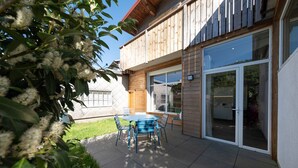 A wooden house with a patio, a round table, and chairs.