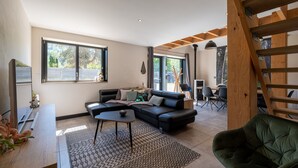 A modern living room with a sectional sofa, a coffee table, and a patterned rug. - Grand Gîte Les Hangars: South-Facing Terrace, 4 Bedrooms, Sauna & Whirlpool – Beds Made, Cleaning Included (Saulxures-sur-Moselotte)