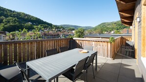 Un patio con tavolo e sedie, un recinto in legno e vista su una collina con case.