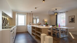 Una cucina moderna con un'ampia finestra, una zona pranzo con tavolo e sedie, e uno specchio tondo appeso al muro.