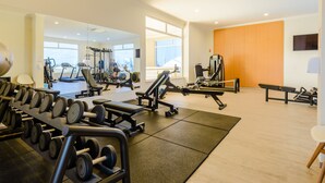 Ett gym med olika typer av träningsutrustning, inklusive löpband, styrketräningsmaskiner och fria vikter.