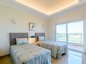 Een hotelkamer met twee bedden, een groot raam en uitzicht op de omgeving.