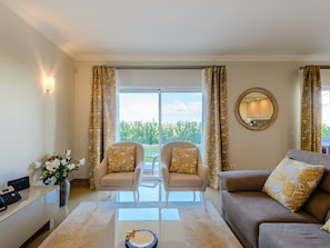 A well-lit living room with a sofa, two armchairs, a coffee table, and a desk with a telephone. - Boavista Golf and Spa Resort - Bayview by Interhome (Lagos)