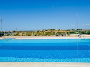 A clear blue pool with lounge chairs and a view of a hilly landscape. - Boavista Golf and Spa Resort - Bayview by Interhome (Lagos)