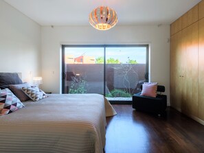 A bedroom with a bed, a nightstand, a dresser, and a view of the outdoors through a sliding door. - Apartment  by Interhome (Quarteira)