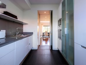A modern kitchen with a built-in oven, a stainless steel sink, and a glass-fronted refrigerator. - Apartment  by Interhome (Quarteira)