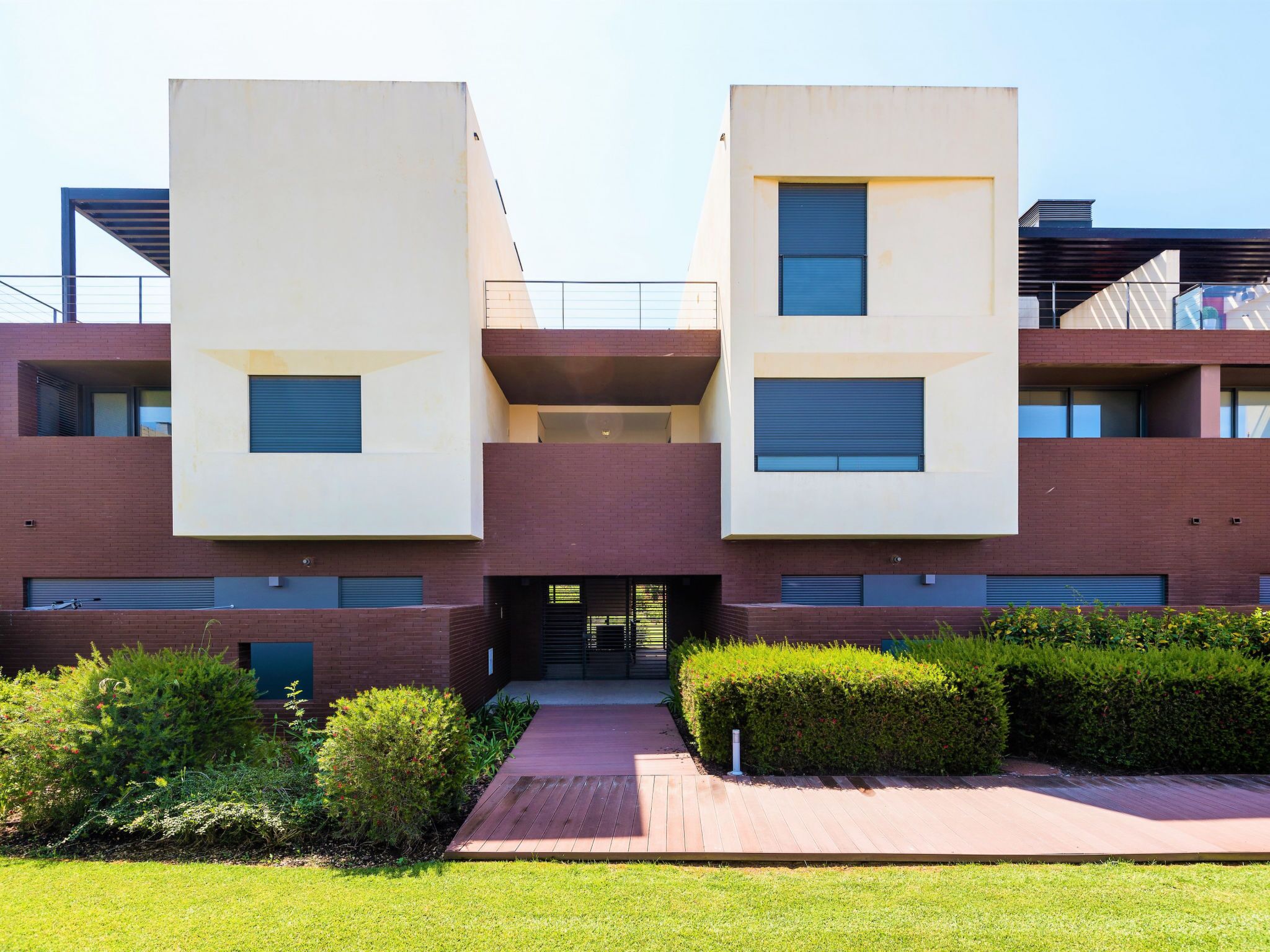 A modern building with two symmetrical sections, a central entrance, and a well-maintained garden area.
