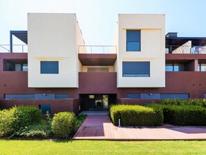 A modern building with two symmetrical sections, a central entrance, and a well-maintained garden area. - Apartment  by Interhome (Quarteira)