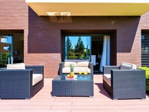A modern outdoor seating area with wicker furniture and a table set with fruits and drinks. - Apartment  by Interhome (Quarteira)