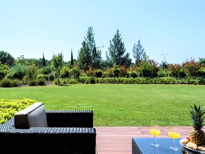 A patio with outdoor furniture, a glass table, and a drink. - Apartment  by Interhome (Quarteira)