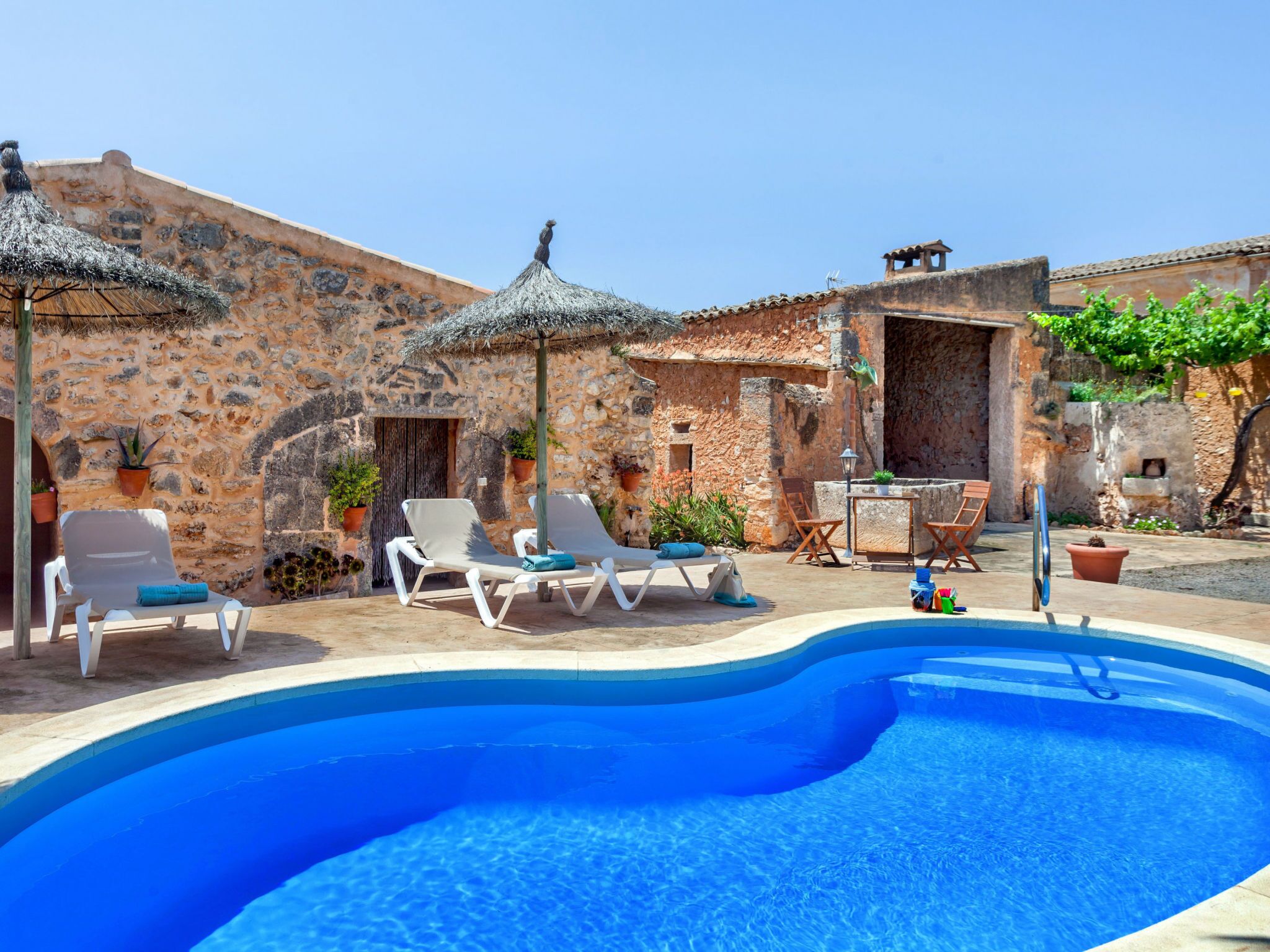 A swimming pool with lounge chairs and umbrellas, surrounded by stone buildings.